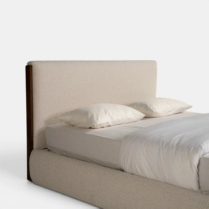 A modern platform bed with a tall upholstered headboard and matching upholstered footboard, dressed in white bedding and two pillows, photographed against a clean white background.